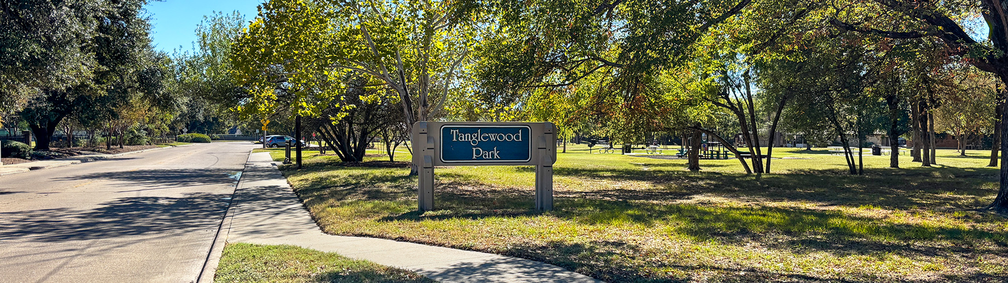 Tanglewood Park sign and trees next to the street.