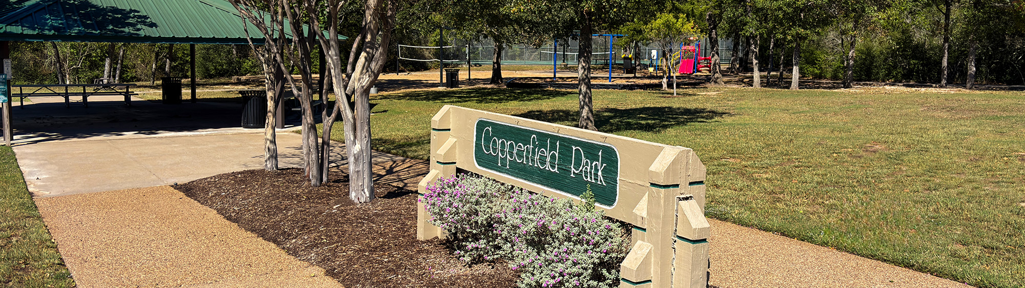 Copperfield Park sign with a pavilion and green area in the background.