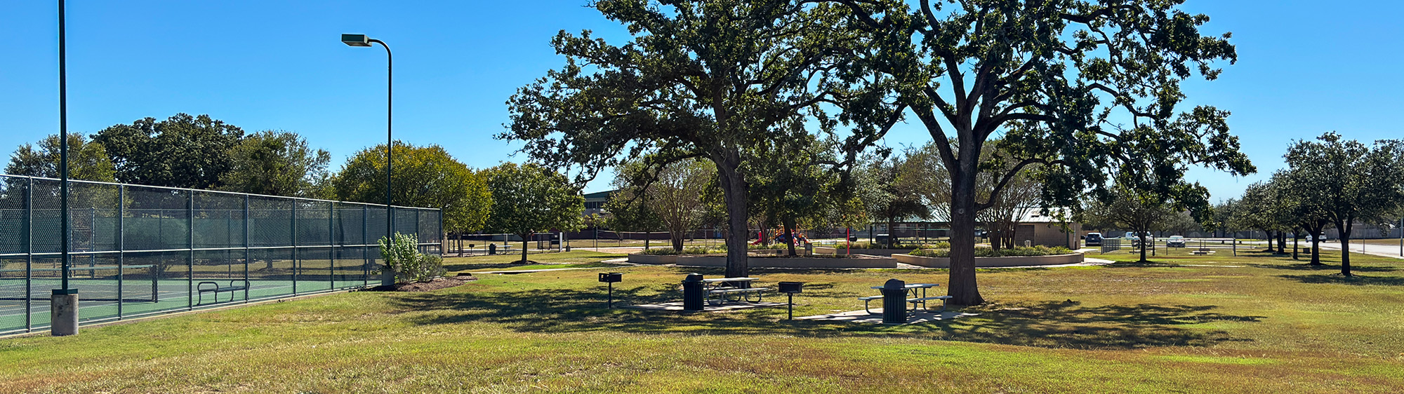 Trees, picnic tables and a tennis court at Tiffany Park.